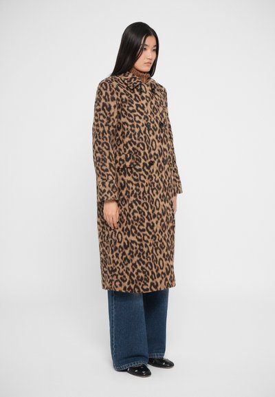 Cappotto di lana con stampa leopardata, colletto, chiusura con bottoni e due tasche frontali. Indossato con pantaloni in denim a gamba larga e scarpe nere.