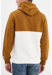 Sudadera con capucha que tiene una parte superior marrón y una parte inferior blanca. Hecha de una tela suave, cuenta con un bolsillo canguro y puños de canalé.
