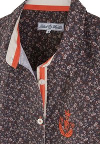 Chemise à motif floral avec fond noir, accents rouges et blancs, fermeture à boutons et logo brodé en orange sur le côté gauche.