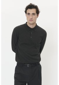 Dunkelgraues langärmliges Poloshirt mit kragenförmigem Ausschnitt und einer Dreiknopf-Leiste. Getragen mit schwarzen Hosen und einem Gürtel. Einfacher, strukturiertes Gewebe.