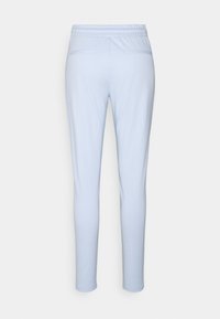 Svetlo modre ožje hlače z elastiko v pasu in dvema zadnjima žepoma na hrbtni strani, prikazane od zadaj na enobarvnem ozadju.