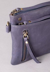 Gray leather clutch with a textured surface, featuring gold-tone hardware, double zippers, and a side strap for carrying.