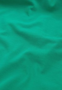 Tissu turquoise lisse avec de subtiles rides et une fine texture côtelée, éclairé uniformément sans autres objets ou détails visibles.