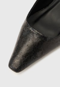 Black pointed-toe shoe with a snakeskin texture and smooth, leather-like finish. Interior features a matte black lining.