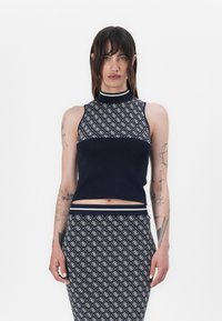 Débardeur en tricot marine sans manches avec une section supérieure à motifs et une section inférieure unie, doté d'un col haut et d'une bordure contrastante.