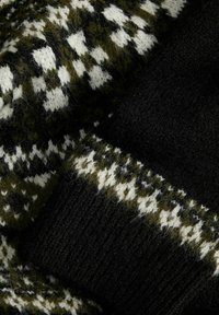 Gestrickter Stoff mit schwarz-weißen und dunkelgrünen nordischen Mustern sowie einem gerippten schwarzen Bündchen.