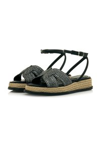 I sandali neri con cinturino intrecciato presentano una suola avvolta in juta, un design aperto sulla punta e un cinturino alla caviglia con dettagli a fibbia. Suola piatta per il massimo comfort.