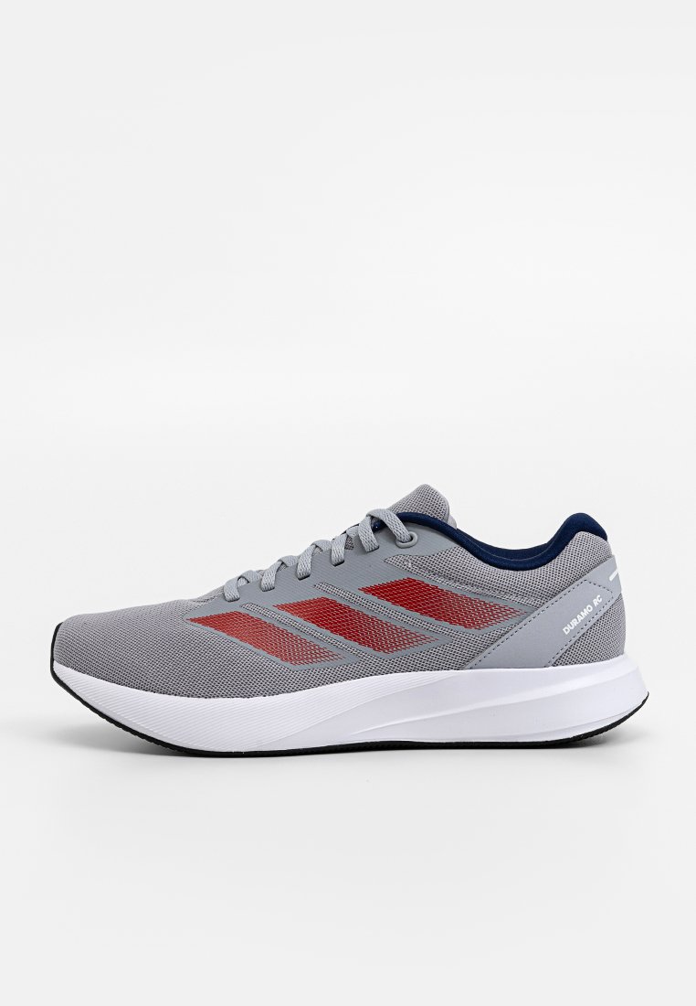 Baskets de sport grises avec une tige en mesh, des rayures d'accent rouges et une semelle blanche rembourrée. Présente un talon bleu marine et des lacets ajustables.