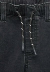 Črne denim hlače z elastičnim pasom, opremljene z vrvico v črno-beli kombinaciji, z gladko teksturo.