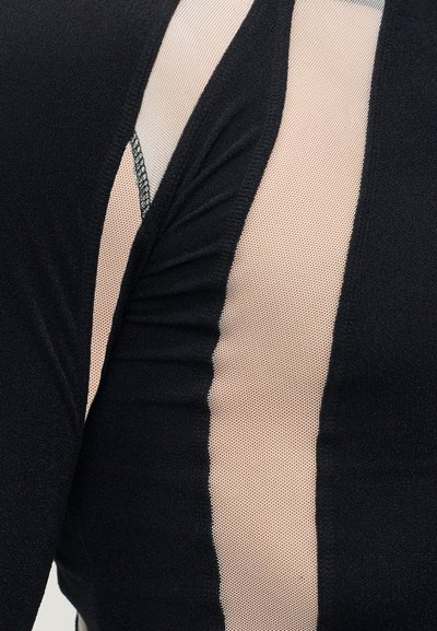 Κοντινή λήψη μαύρου υφάσματος με ρίγες από γυμνό διχτυωτό ύφασμα και ένα μικρό τμήμα διακοσμητικής τρέσσας από κάτω.