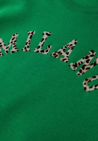 Grøn bomulds-sweatshirt med ordet "MILANO" i et leopardmønster. Glat tekstur med en klassisk rund halsudskæring.