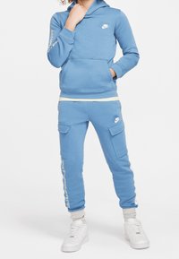 Blue Nike hoodie with long sleeves and front pocket; paired with blue cargo pants featuring two side pockets and white accents. White sneakers.