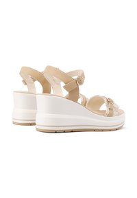Sandali con zeppa, suola bianca, cinturini in pelle beige, fibbia alla caviglia e dettagli decorativi. Presentano una soletta testurizzata per una presa migliore.