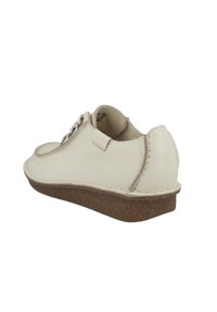 Scarpa in pelle bianca con punta rotonda, dettagli cuciti e suola leggera di tipo sughero marrone chiaro. Caratterizzata da un dettaglio con lacci e design minimalista.