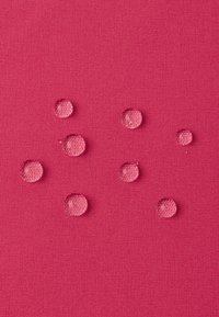 Tissu texturé rose vif avec six gouttes d'eau à la surface, mettant en valeur la résistance à l'eau et les finitions lisses et brillantes des perles.