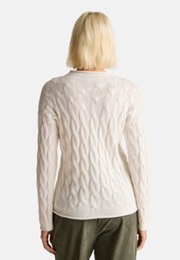 Bílý svetr s pleteným vzorem, dlouhými rukávy, kulatým výstřihem a přiléhavým střihem.