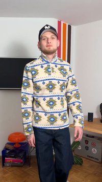 Fleece pullover in cream with blue and green geometric patterns, zip collar, and ribbed cuffs, paired with dark jeans.