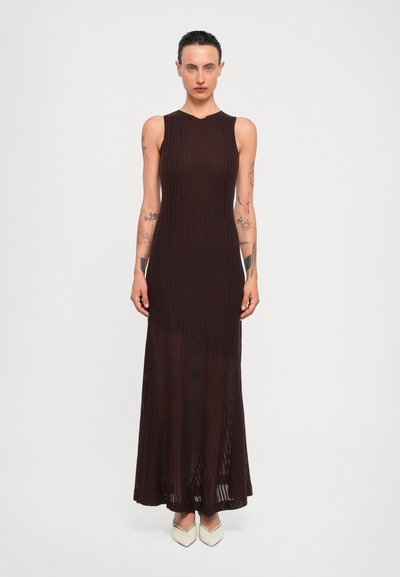 Robe maxi en tricot côtelé marron avec un design sans manches et un col haut, présentant une partie inférieure transparente et une silhouette droite.