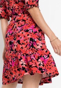 Květinové šaty v červené, růžové a černé barvě. Mají nabírané rukávy, volánový lem a přiléhavý pas. Měkká, lehká látka s výrazným vzorem.