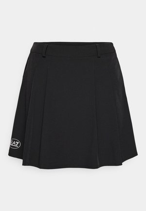 Black pleated skirt featuring a flat waistband, smooth texture, and a logo patch on the lower left side. Minimalist design with no patterns.