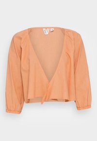 Blusa avvolgente in misto lino di colore pesca, leggera, con scollatura a V profonda e maniche lunghe a sbuffo, dotata di polsini elasticizzati per una vestibilità comoda.