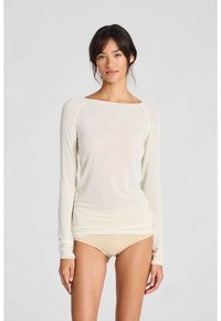 Langärmliges, leichtes Oberteil in Creme mit Rundhalsausschnitt und figurbetontem Schnitt. Glatte Oberfläche, minimale Nähte, einfarbiger Stoff.