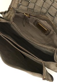 Interno di una borsa in suede grigia intrecciata con multiple tasche, fodera liscia e una cerniera in tono oro con un piccolo etichetta del marchio all'interno.