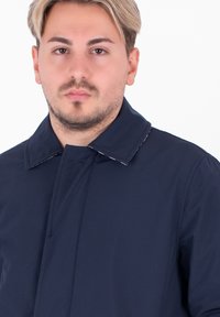 Giacca blu navy con un design semplice, caratterizzata da un colletto a punta e cuciture visibili. Tessuto leggero e liscio con una vestibilità moderna.