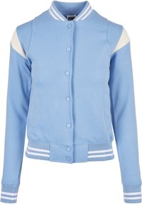 Ljust blå varsityjacka med vita axelpartier, knapplist framtill, ribbad krage, mudd och fåll med vita ränder.