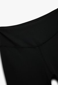 Leggings neri con una superficie liscia, dotati di un'alta vita e cuciture piatte. Il design è minimalista, senza motivi visibili.