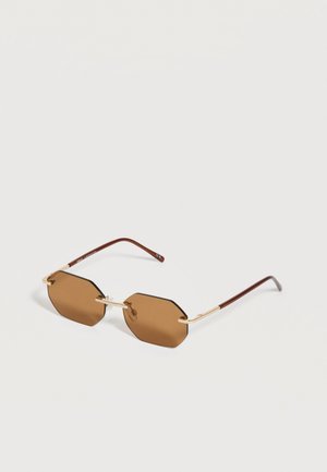 Lunettes de soleil octogonales brunes sans monture avec pont en métal doré et branches marron sur fond blanc.
