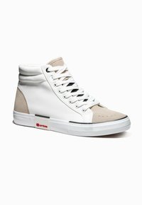 Zapatillas altas con parte superior sintética blanca y acentos de ante beige. Incluyen cordones blancos planos, un collar acolchado y una suela de goma. Detalle del logo en rojo.