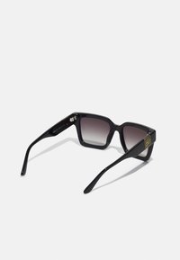 Black square sunglasses with gradient lenses, glossy plastic frame, straight temples, and small gold logo detail on the side.