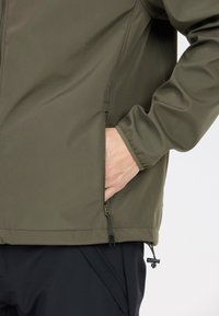 Olivengrøn jakke med en glat, mat finish. Har en sidelomme, justerbar kant og elastiske manchetter for en sikker pasform.