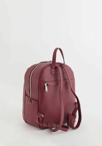 Sac à dos en cuir rouge texturé avec un dessus zippé, des bretelles réglables et une poche avant. Doté d'accents en métal argenté et d'une poignée de transport.