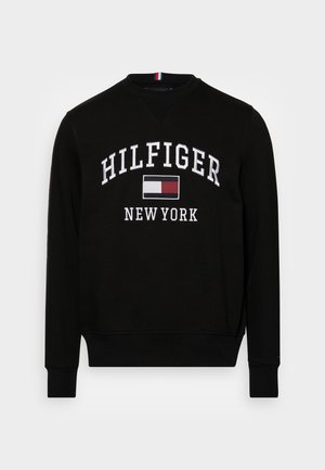 Sudadera negra con cuello redondo, que presenta un texto bordado en blanco "HILFIGER NEW YORK" y un parche de logo en rojo y azul. Textura de tela suave.