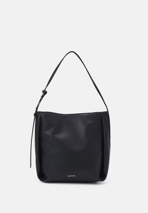 Sort skuldertaske i læder med en enkelt justerbar strop og lille Calvin Klein-logo nederst i midten.