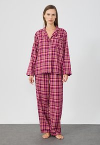 Rúžová károvaná pyžamová súprava s dlhými rukávmi a nohavicami, s button-up košeľou a náprsnom vrecku. Mäkká tkaninová textúra.