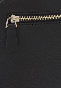 Černá texturovaná kožená taška s částí se zlatým zipem a táhlem, představující jemný vzor zrn a hladký povrch.