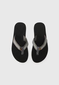 Svarte flip-flops med teksturerte mørk grå stropper som har et geometrisk mønster, og en liten oransje logo på hver stropp. Minimalistisk design.