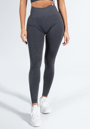 Leggings grigi alti in vita, realizzati in un morbido tessuto testurizzato, che offrono una vestibilità aderente e una vita liscia. Abbinati a sneaker bianche.
