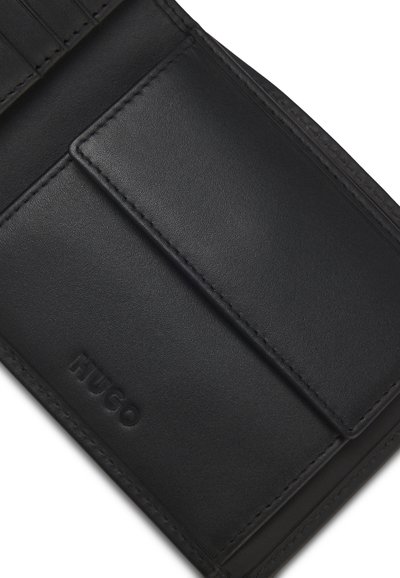 Portefeuille en cuir noir avec rabat de poche avant, embossé du nom de la marque HUGO dans le coin inférieur.