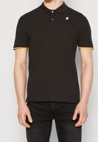 Czarna koszulka polo z krótkimi rękawami, wyposażona w trzypoziomowy zamek, kolorowe akcenty w odcieniach żółtym i niebieskim na mankietach oraz logo na klatce piersiowej.