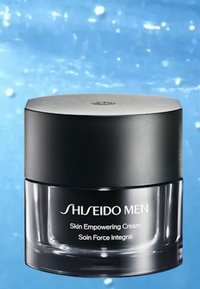 Shiseido Men Skin Empowering Cream sisällä pyöreässä, kirkkaassa lasipurkissa, jossa on mattamusta kansi. Etiketti etupuolella on valkoista tekstiä.