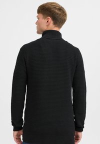 Schwarzer Strickpullover mit hohem Kragen, gerippten Bündchen und strukturiertem Stoffmuster. Lässige Passform mit geradem Rückendesign.
