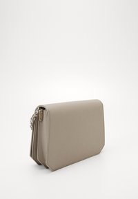 Beige taske i kunstlæder med en rektangulær form. Har en sølv kæderem, elegante linjer og en flaplukning. Minimalistisk design.