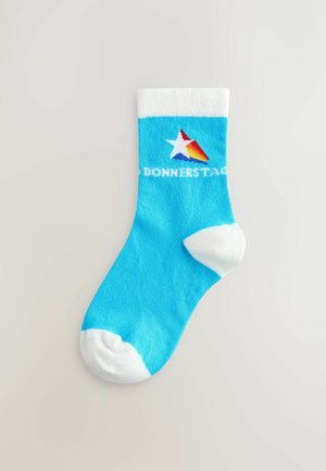 Calzino di cotone blu con risvolto e punta bianchi, caratterizzato da un logo a stella multicolore e la scritta "DONNERSTAG" in bianco.