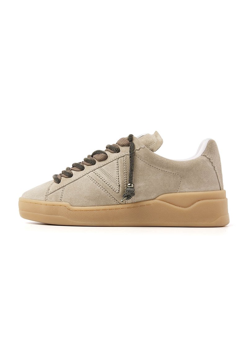 Beige suede sneakers with a low profile, textured rubber sole, and braided laces featuring metallic accents. White inner lining.