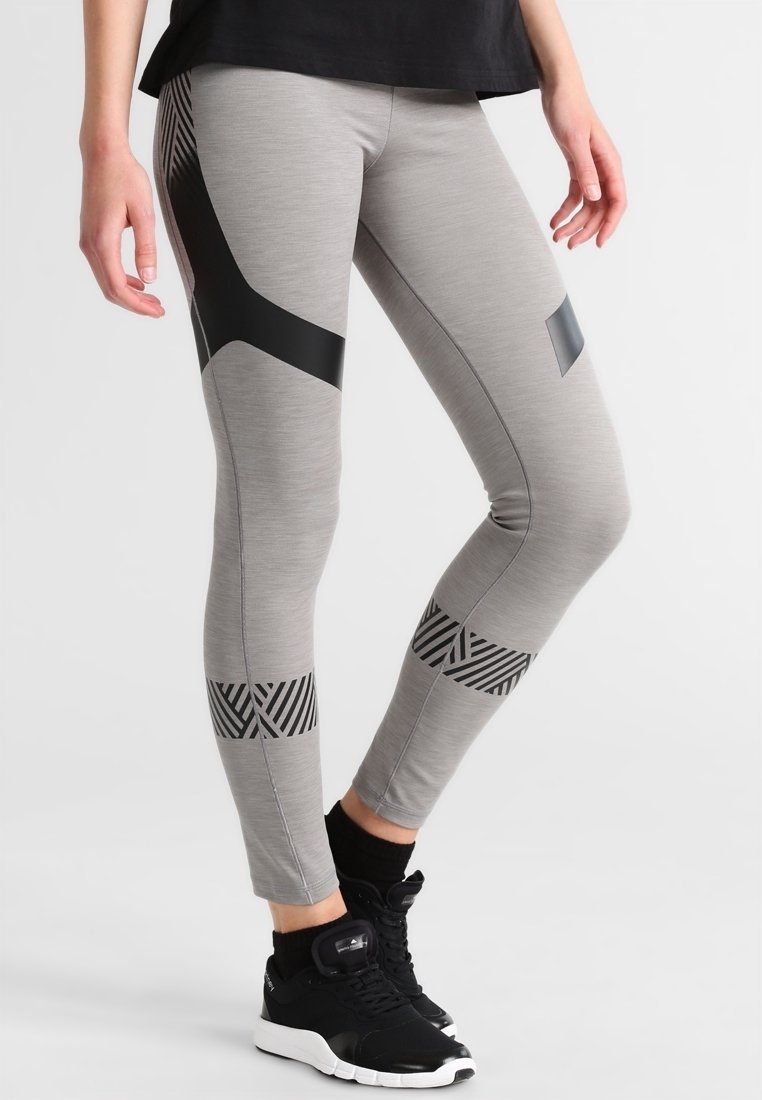 Leggings gris clair avec des accents géométriques et des rayures noires, fabriqués dans un tissu extensible, avec un design ajusté et une longueur jusqu'à la cheville.