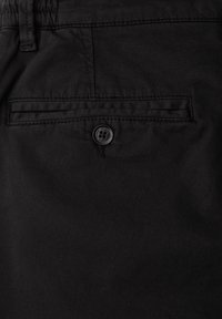 Pantalon en coton noir avec une poche arrière à fermeture boutonnée et des détails couture. Texture lisse avec un motif uni.